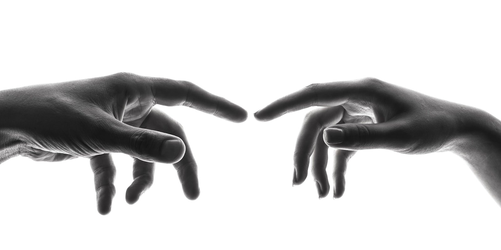 Two hands reaching toward each other, fingers nearly touching